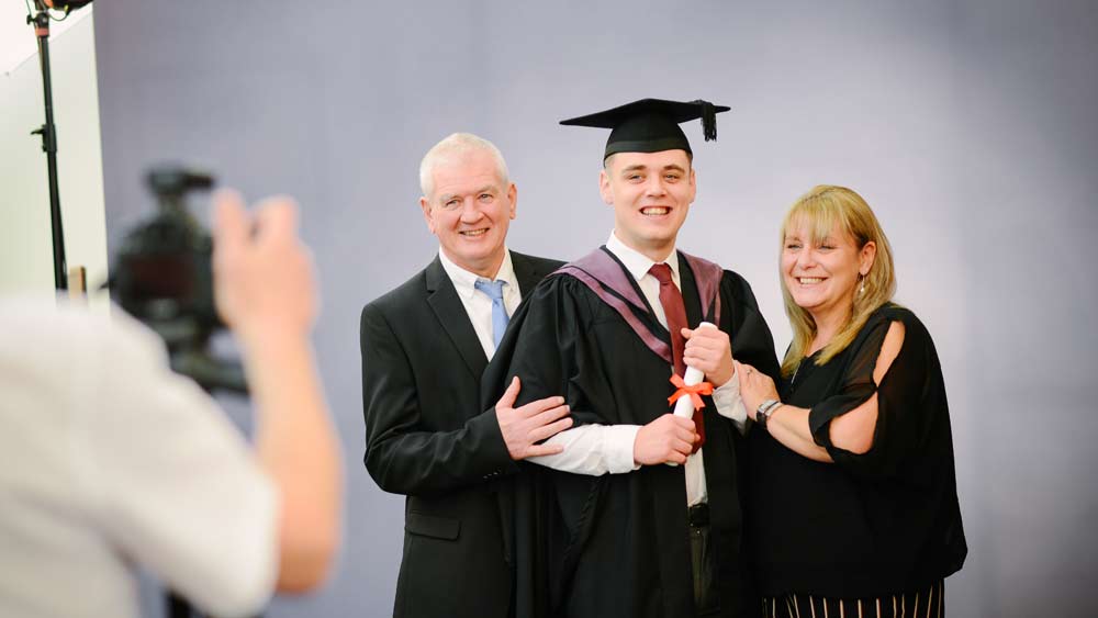 A graduate and his parents pose for official photos