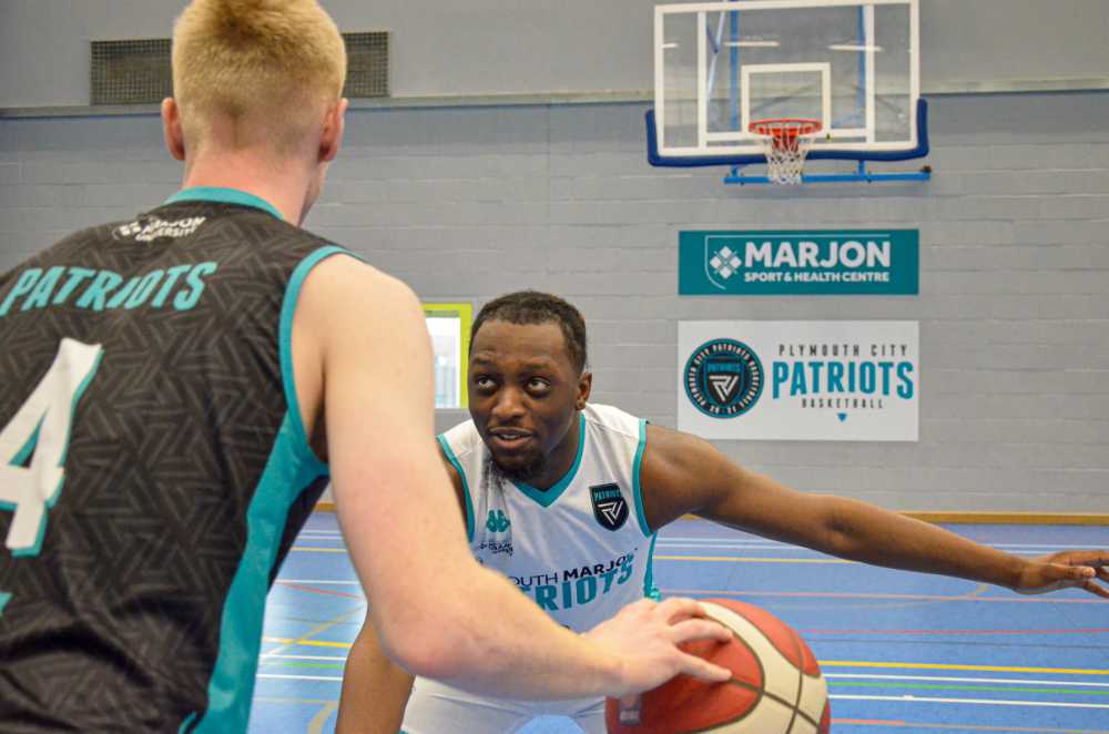 Two players in Plymouth Patriots kit playing basketball on a Marjon court