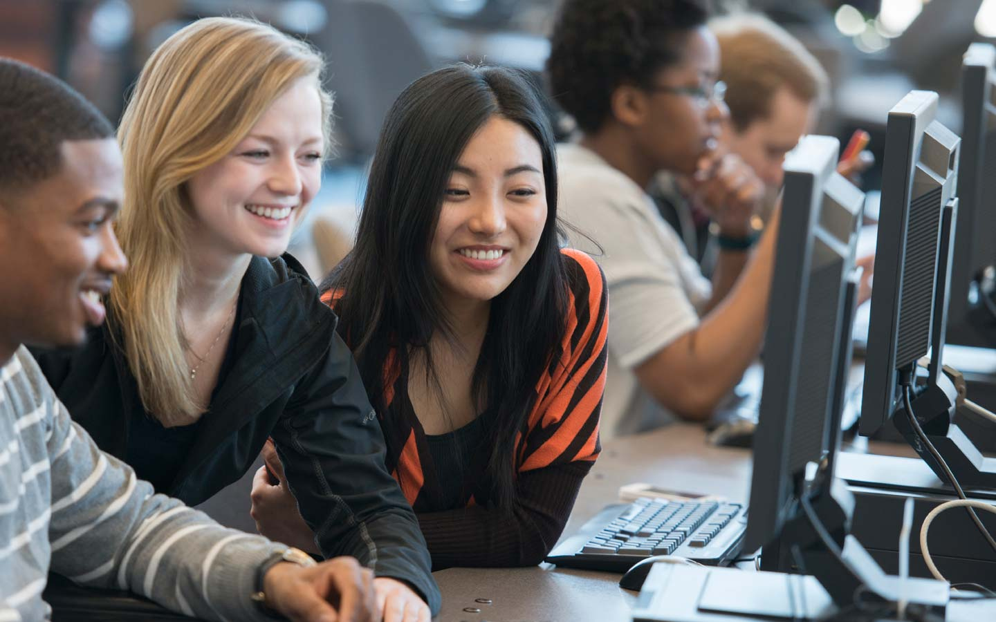 Three students smiling and looking at a screen