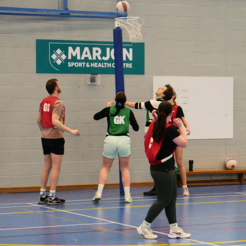 A group of students playing netball in a sport hall