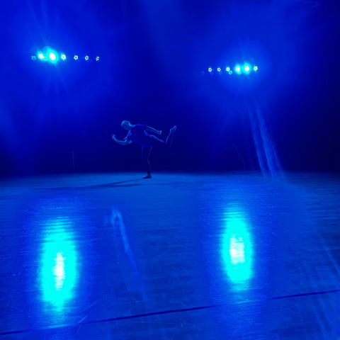 A school child performing under blue lights