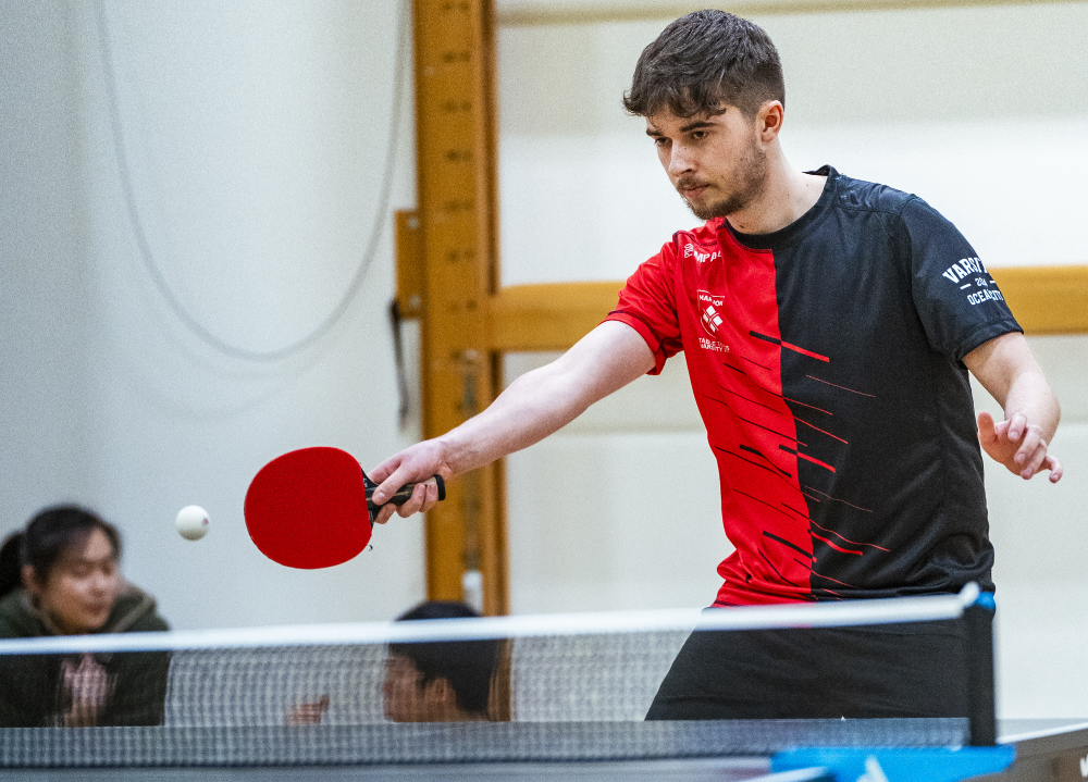 A team Marjon table tennis player hits the ball over the net.